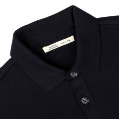 Close-up image of the Navy Blue Wool Milano Knitted Overshirt by Maurizio Baldassari, featuring buttons. A label inside the collar reads "MAURIZIO BALDASSARI made in Italy," showcasing its Milano stitch craftsmanship and pure virgin wool fabric.