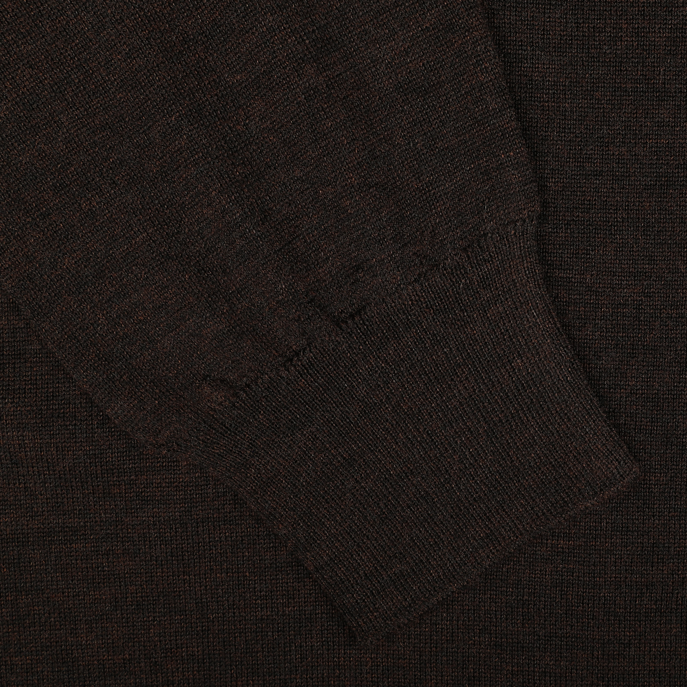 Close-up of a dark brown knitted sleeve cuff on a textured fabric background, showcasing the contemporary fit of this Brown Melange 16 Gauge Merino Wool Polo Shirt by Mauro Ottaviani.