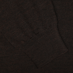 Close-up of a dark brown knitted sleeve cuff on a textured fabric background, showcasing the contemporary fit of this Brown Melange 16 Gauge Merino Wool Polo Shirt by Mauro Ottaviani.