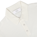 A Cream 16 Gauge Merino Wool Polo Shirt by Mauro Ottaviani is laid flat. The shirt has a plastic tag with the name "Mauro Ottaviani" and "Made in Italy" on it. The collar and three front buttons are clearly visible, showcasing its contemporary fit.