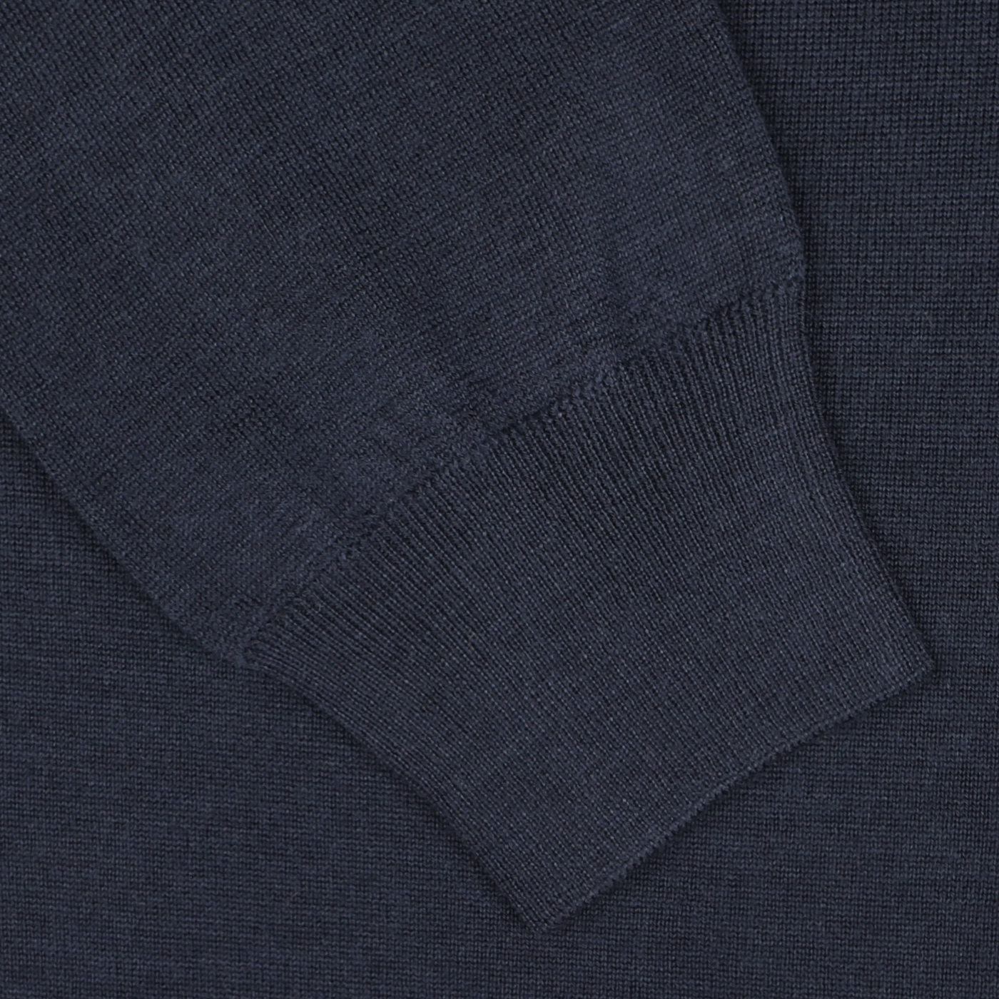 Close-up of the sleeve and cuff of a dark blue, 16 gauge Merino wool long-sleeve polo shirt by Mauro Ottaviani, showcasing the intricate texture and stitching details.