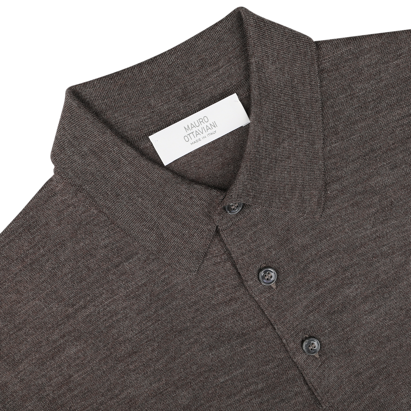 Close-up of a light brown collared, long-sleeve "Light Brown 16 Gauge Merino Wool Polo Shirt" by Mauro Ottaviani, with buttons and a white label featuring text.