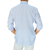 A person viewed from behind, wearing a Mazzarelli Blue Striped Organic Linen BD Regular Fit Shirt and light-colored pants.