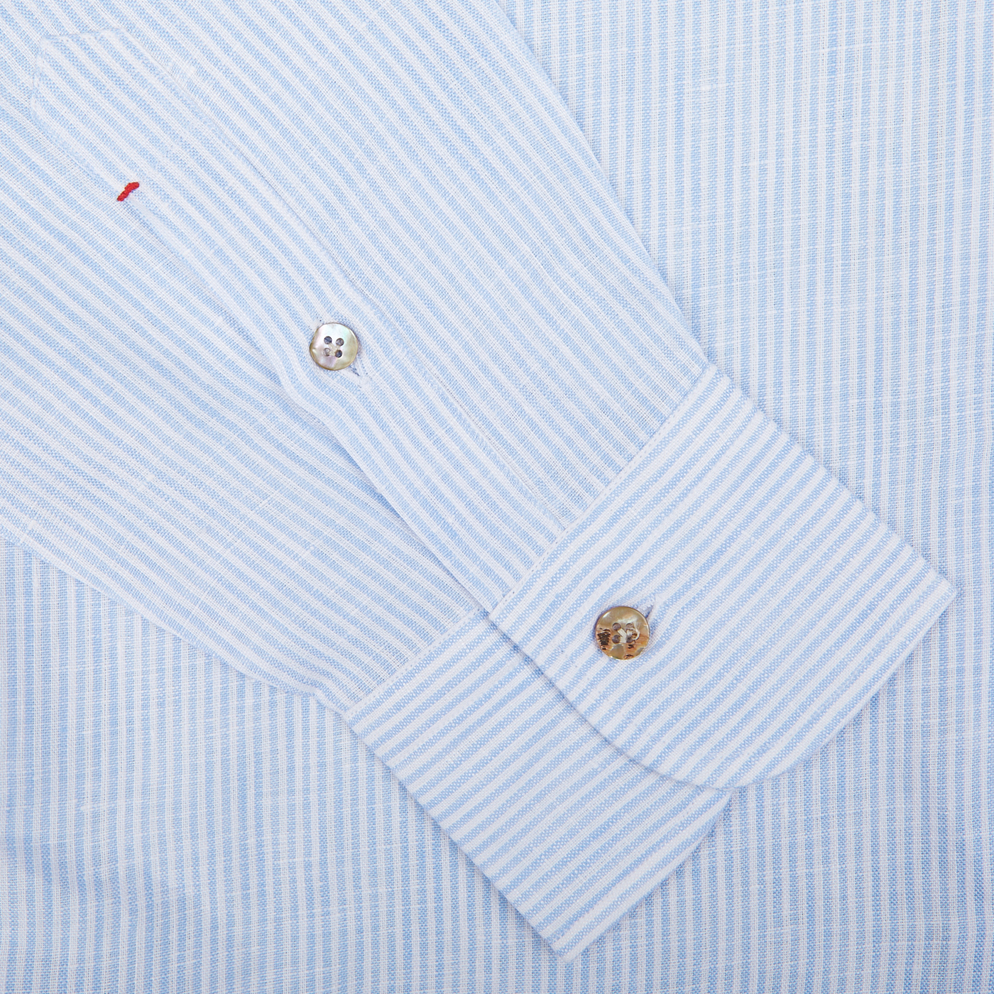 A close-up of a Mazzarelli Blue Striped organic linen summer shirt with a focus on the cuff and button.
