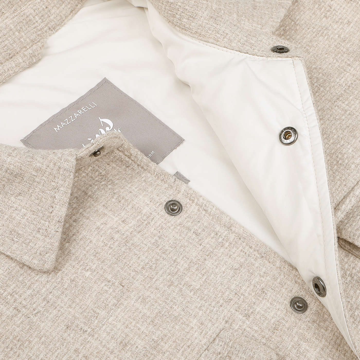 Close-up of the Cream Beige Wool Cashmere Padded Overshirt by Mazzarelli, this button-up shirt showcases a visible label on the inside collar. Ideal as a seasonal overshirt, it seamlessly combines style with versatility.