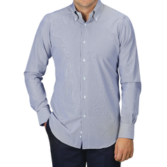 A person dressed in a Dark Blue Thin Striped Cotton BD Slim Shirt by Mazzarelli and dark pants stands against a gray background, showcasing the timeless craft of an Italian shirtmaker.