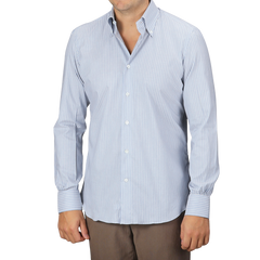 The individual is dressed in a Mazzarelli Denim Blue Striped Cotton BD Regular Shirt, featuring long sleeves and a button-down collar, perfectly paired with brown pants to effortlessly enhance their style.