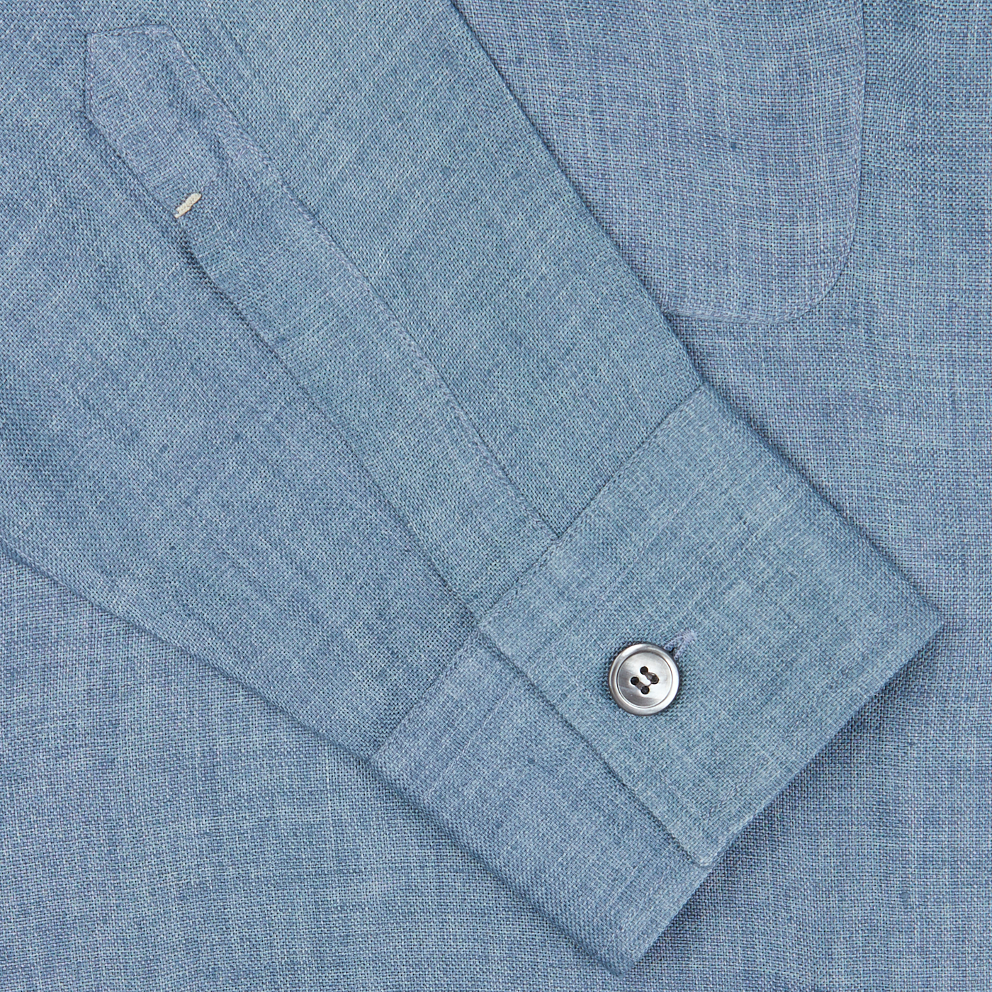 Close-up of a Mazzarelli Indigo Blue Organic Linen Four Pocket Overshirt cuff with a silver button and detailed stitching.