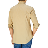Man standing with his back facing the camera, wearing a Mazzarelli Khaki Beige Cotton Gabardine Regular Fit Shirt and blue jeans.