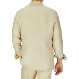 Rear view of a person wearing a Khaki Beige Organic Linen Four Pocket Overshirt and matching pants by Mazzarelli, standing against a plain gray background.