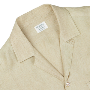Close-up of a Khaki Beige Organic Linen Four Pocket Overshirt with a Mazzarelli brand label on the collar, highlighting the textured fabric and collar design.