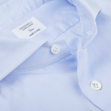 Close-up of a light blue Mazzarelli Light Blue Cotton Twill Cut Away Slim Shirt, focusing on the cutaway spread collar label reading "MAZZARELLI Classic Fit made in Italy" and two white buttons.