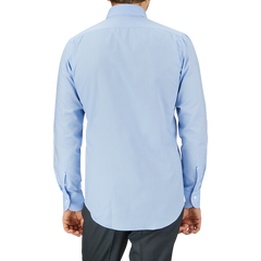 Rear view of a man wearing a Mazzarelli Light Blue Royal Oxford BD Slim Shirt and dark trousers, standing against a gray background.