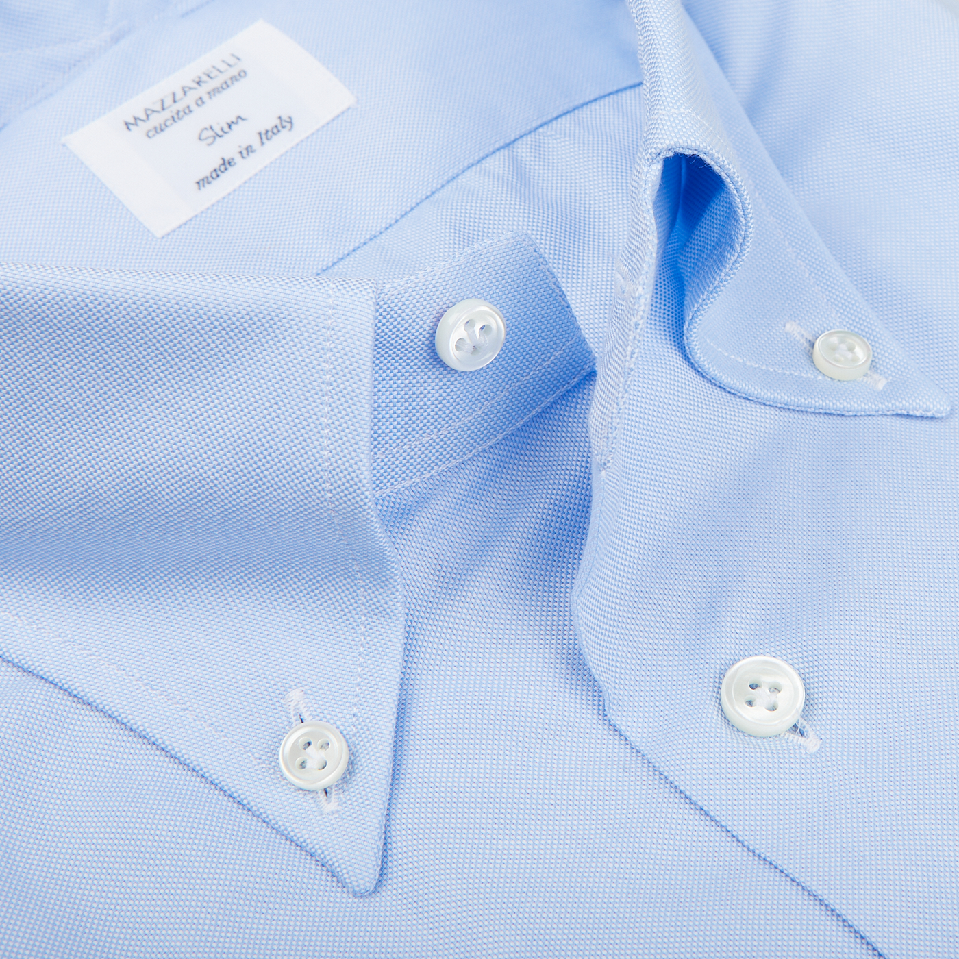 Close-up of a Mazzarelli Light Blue Royal Oxford BD Slim Shirt with white buttons, featuring a collar label that reads "Napoli Tailored - Made in Italy.