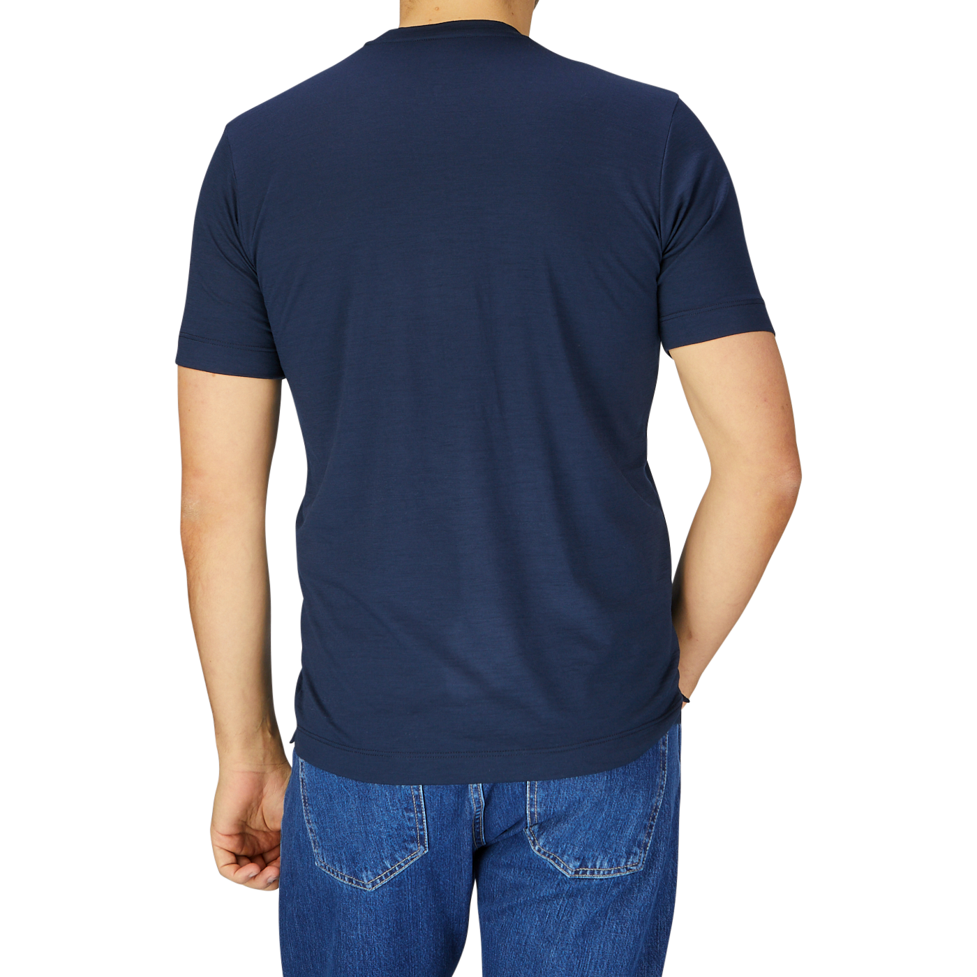 Rear view of a man wearing a Mazzarelli Navy Blue Merino Wool T-Shirt and blue denim jeans, standing against a light gray background.