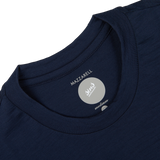 Close-up of a Navy Blue Merino Wool T-shirt's label showing the brand "Mazzarelli" in a medium, slim fit size, set against a white background.