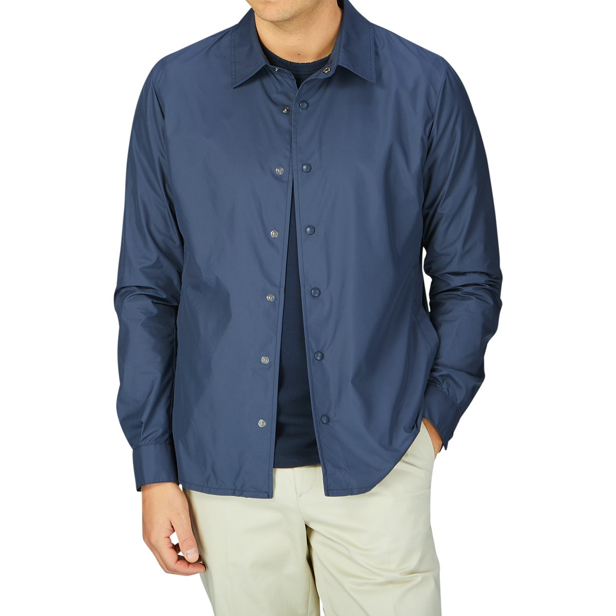 A man wearing a Mazzarelli navy blue nylon water resistant overshirt and cream trousers.