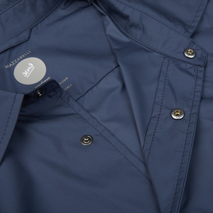 Close-up view of a Mazzarelli navy blue technical overshirt with snap buttons and a brand label, made from water-resistant nylon.