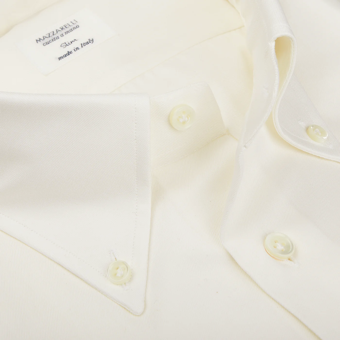 A close-up shows an off-white slim shirt made from pure cotton twill, featuring a pointed collar. The label displays "Mazzarelli" and highlights that it's "Made in Italy.