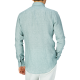 A person standing with their back to the camera, wearing a Teal Green Organic Linen BD Slim Shirt by Italian shirtmaker Mazzarelli and white pants.