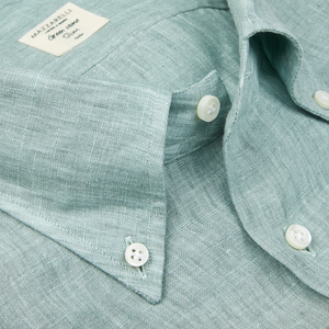Close-up of a textured teal green organic linen slim shirt with a collar and a visible label by Italian shirtmaker Mazzarelli.