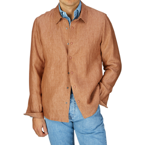 Man wearing a Mazzarelli terracotta brown organic linen overshirt with an open collar, paired with light blue jeans.