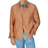 Man wearing a Mazzarelli terracotta brown organic linen overshirt with an open collar, paired with light blue jeans.