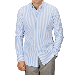 A man wearing a Mazzarelli White Blue Bengal Striped BD Slim Shirt and gray pants stands against a plain background.