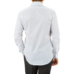 A man viewed from behind, wearing an untucked Mazzarelli White Cotton Twill Cutaway Slim Shirt and dark trousers against a gray background.