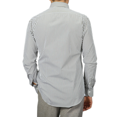 A person dressed in a white and green striped shirt from Mazzarelli, an Italian shirtmaker, faces away. The pure cotton shirt is tucked into gray pants.