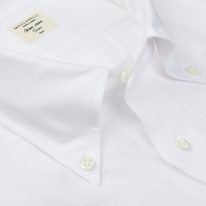 Close-up of a Mazzarelli white organic linen BD slim shirt with a collar label displaying the brand "Italian shirtmaker Mazzarelli, from the Green Stone Collection.