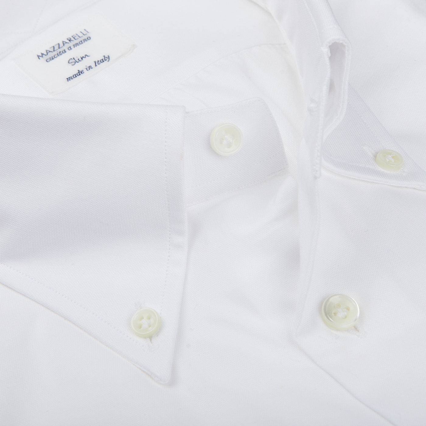 Close-up of a Mazzarelli White Royal Oxford BD Slim Shirt with a label reading "MAZZARELLI Classico, made in Italy" on the collar.
