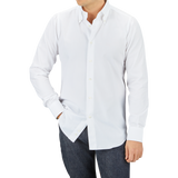 Man wearing a Mazzarelli White Royal Oxford BD Slim Shirt and dark jeans standing against a gray background.