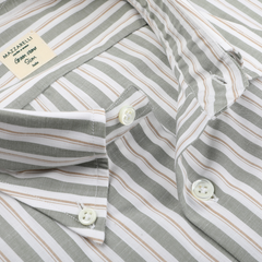 Close-up of a Mazzarelli Green Vintage Wide-Striped Cotton BD Shirt with white, gray, and beige lines, featuring white buttons and a brand label on the inside collar. Crafted from organic cotton by esteemed Italian shirtmaker Mazzarelli.