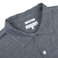 Close-up of the Denim Blue Cotton Chambrey 06 CH Shirt by Merz b. Schwanen, featuring a visible collar and brand label, made from organic cotton for an eco-friendly touch.