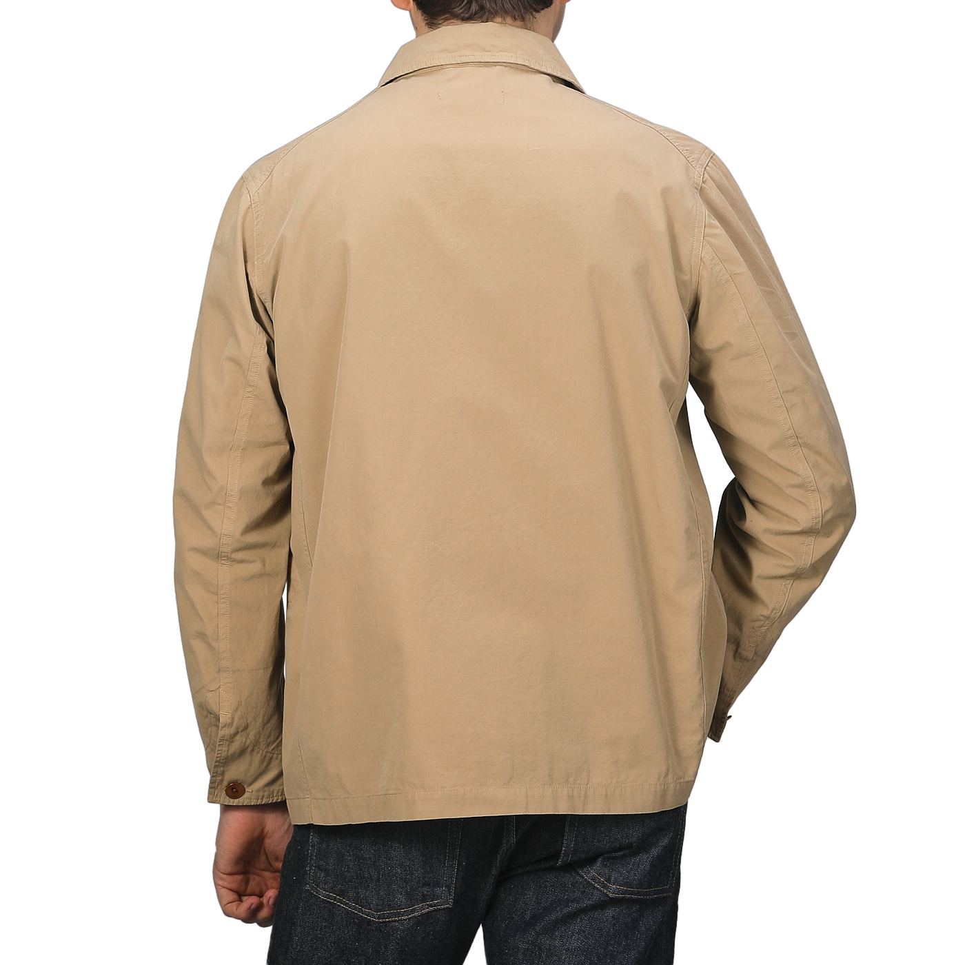 A person wearing a Khaki Beige Cotton Poplin 02 Jacket by Merz b. Schwanen, featuring vegan corozo buttons, and dark jeans stands with their back to the camera against a gray background.