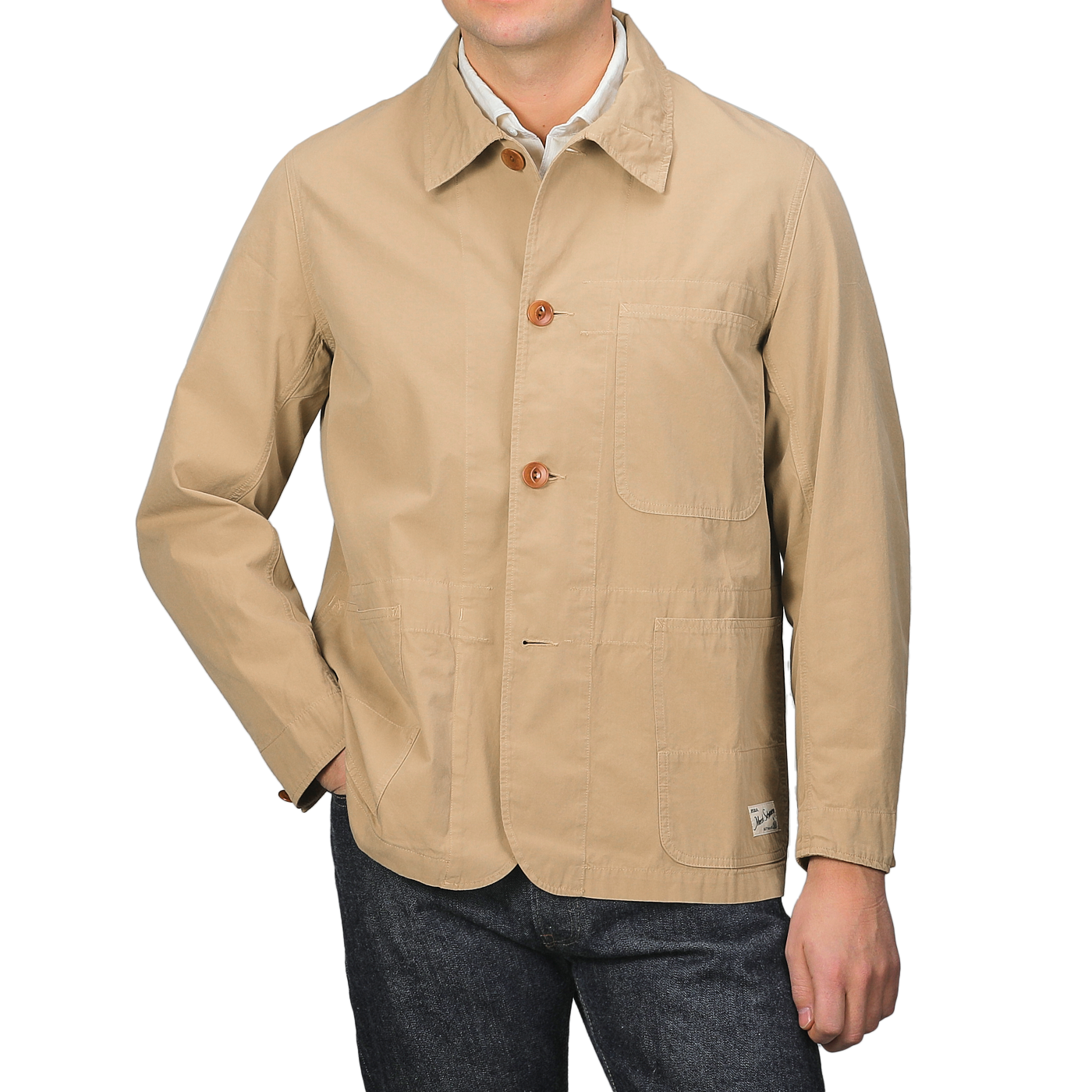 A person in the Merz b. Schwanen's Khaki Beige Cotton Poplin 02 Jacket featuring vegan corozo buttons and front pockets, paired with blue jeans.