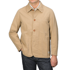 A person in the Merz b. Schwanen's Khaki Beige Cotton Poplin 02 Jacket featuring vegan corozo buttons and front pockets, paired with blue jeans.