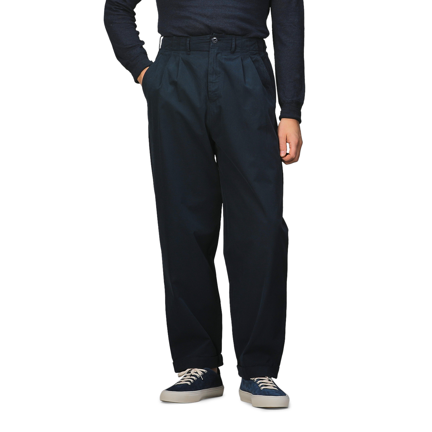 A person stands with hands in pockets wearing Merz b. Schwanen Navy Blue Cotton Poplin 03 Pants, a dark long-sleeve shirt crafted from organic cotton for added comfort, blue and white sneakers.