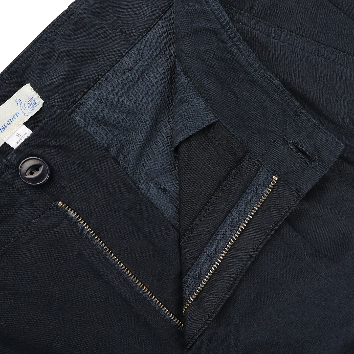 Close-up of a pair of Navy Blue Cotton Poplin 03 Pants from Merz b. Schwanen, unzipped to show the button and waistband with a visible label, highlighting their comfort and versatility.