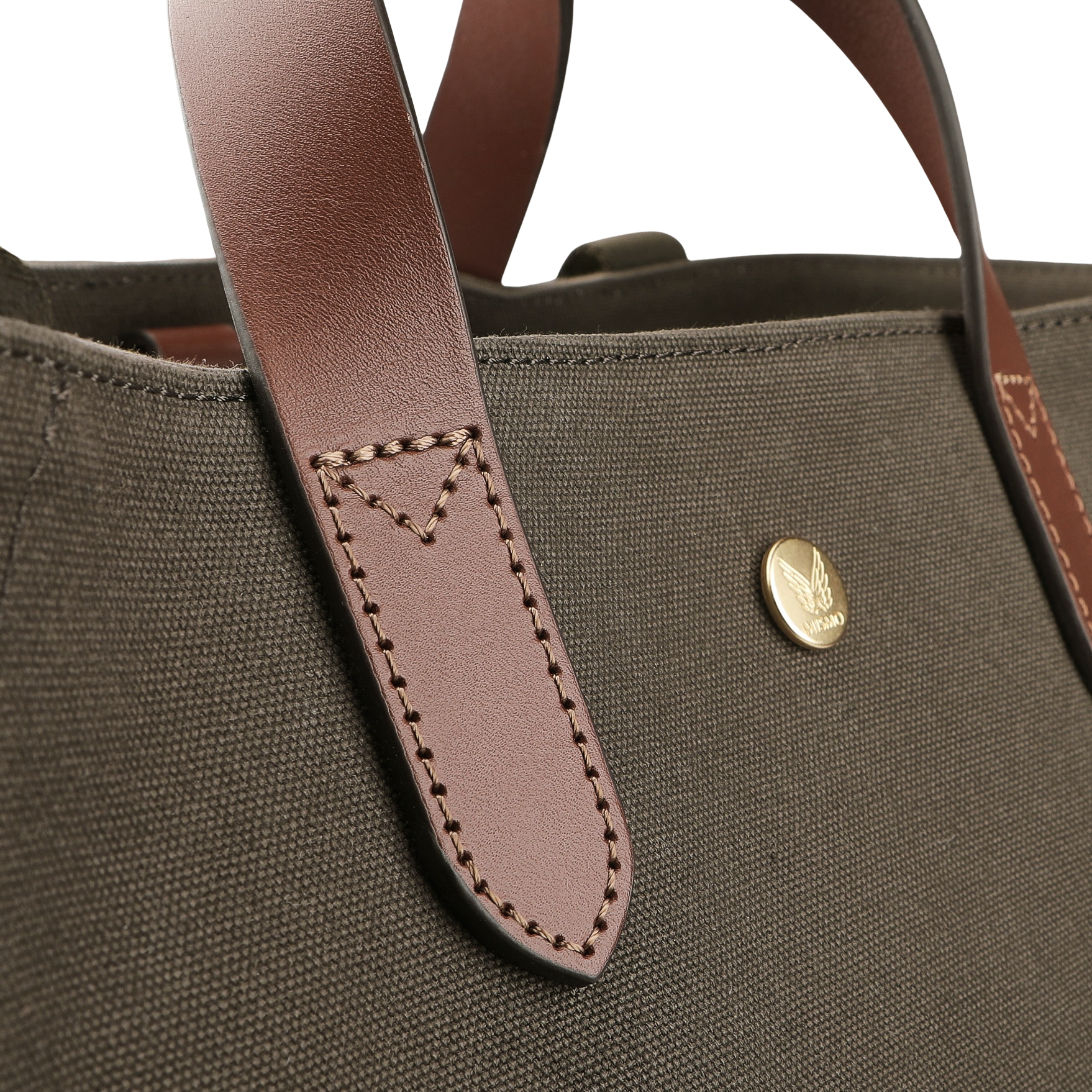 Close-up of the Army Cuoio M/S Canvas Verve Tote Bag by Mismo, showcasing a brown leather handbag strap with stitching and a round gold emblem, highlighting exquisite leather details against the brown fabric.