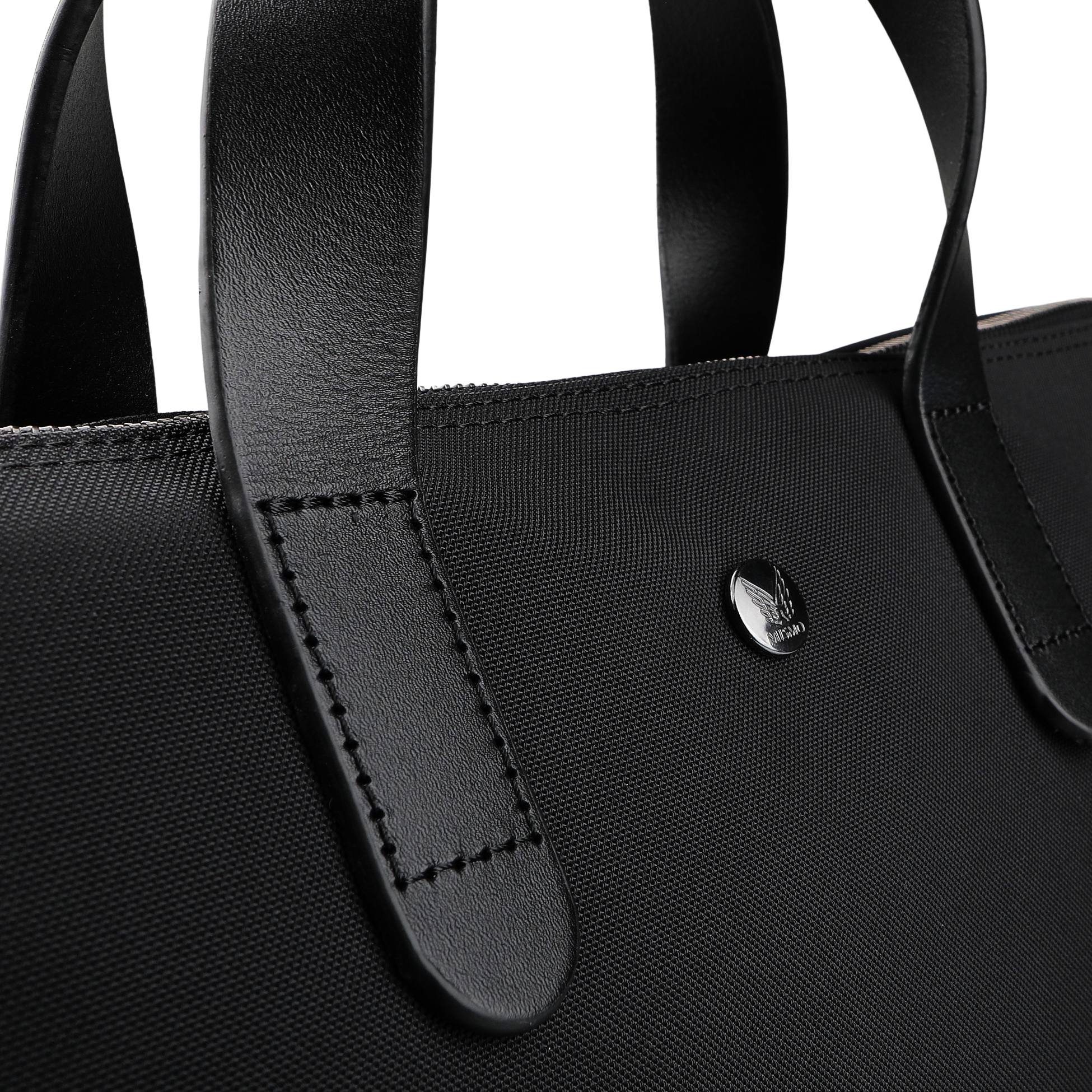 Close-up of the Eclipse Black M/S Nylon Brief by Mismo, an urban handbag crafted from ballistic nylon with sturdy leather handles and a small circular metal emblem.