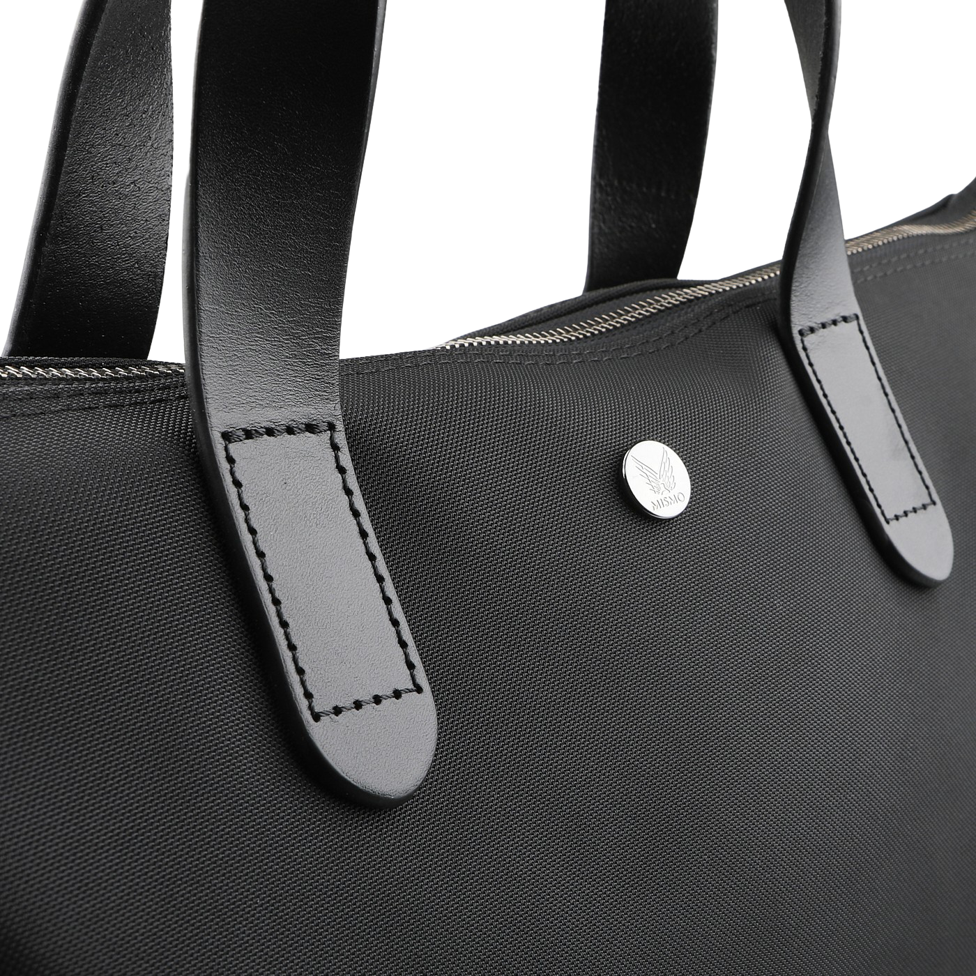 The Eclipse Black M/S Nylon Shopper by Mismo is an urban tote made from waterproof ballistic nylon, featuring sturdy full-grain leather handles, a visible zipper, and a small round metal emblem with an engraved logo—perfect for style and durability.