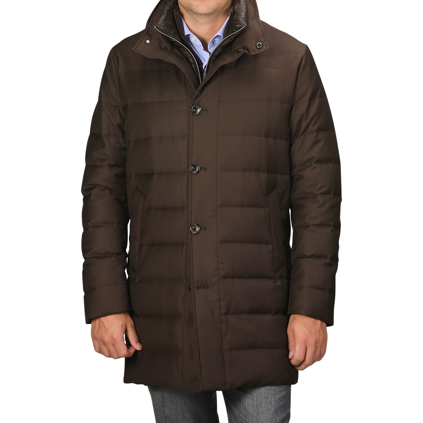 A person wearing a dark brown, Montecore Brown Super 120s Wool Batavia Padded Coat featuring buttons stands against a grey background. The Italian outerwear boasts a high collar and is paired with blue jeans.