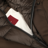 Close-up of a Montecore Brown Super 120s Wool Batavia Padded Coat, showcasing an unzipped pocket with the inner white lining and a red fabric label visible.