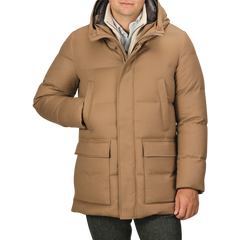 A person wearing the Camel Beige VBC Wool Flannel Padded Parka with a high collar and hood, placing one hand in a front pocket. This stylish piece from Italian outerwear specialist Montecore seamlessly blends functionality with sophistication.