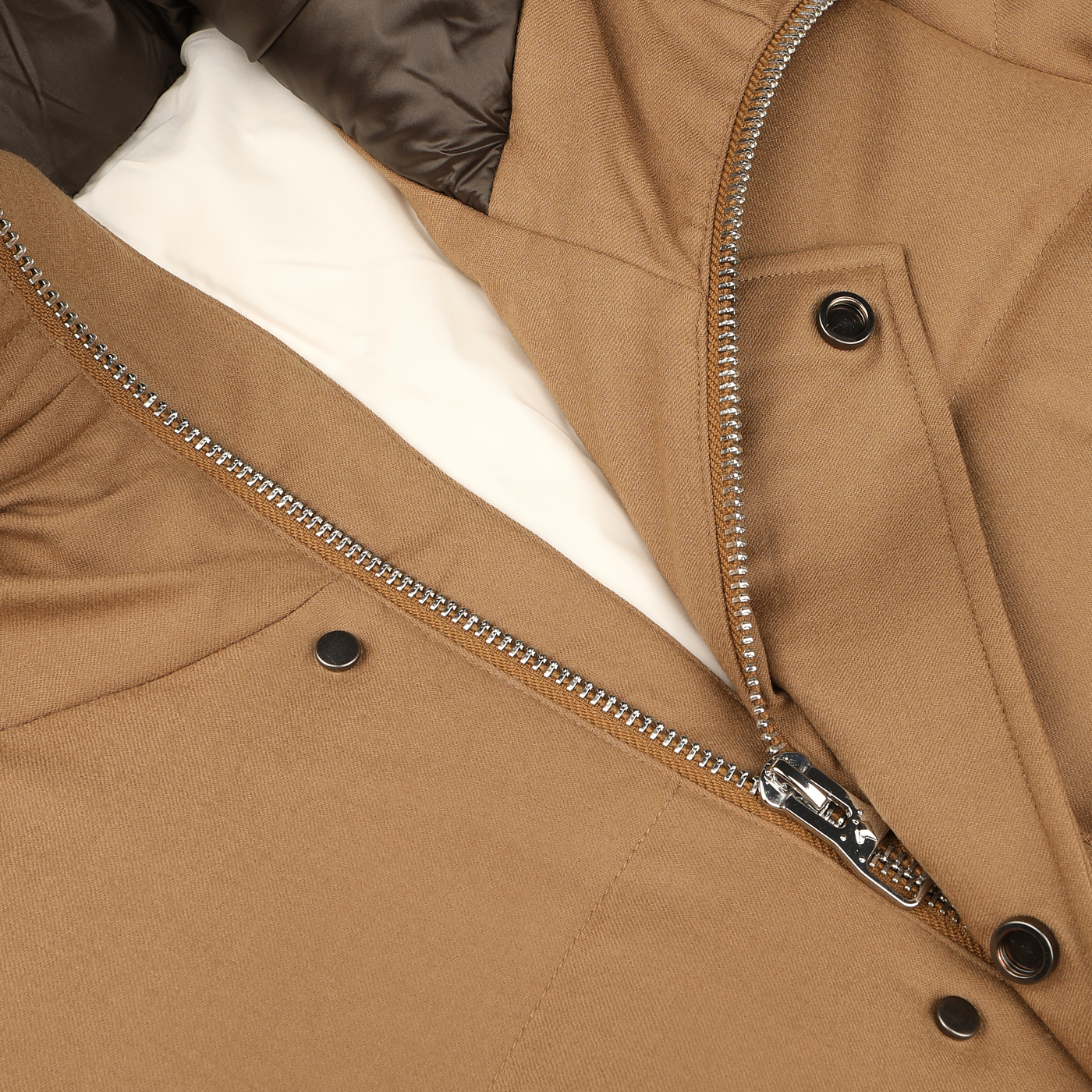 Close-up of a partially unzipped Camel Beige VBC Wool Flannel Padded Parka by Montecore, displaying the metal zipper and black snap buttons on a fabric surface.