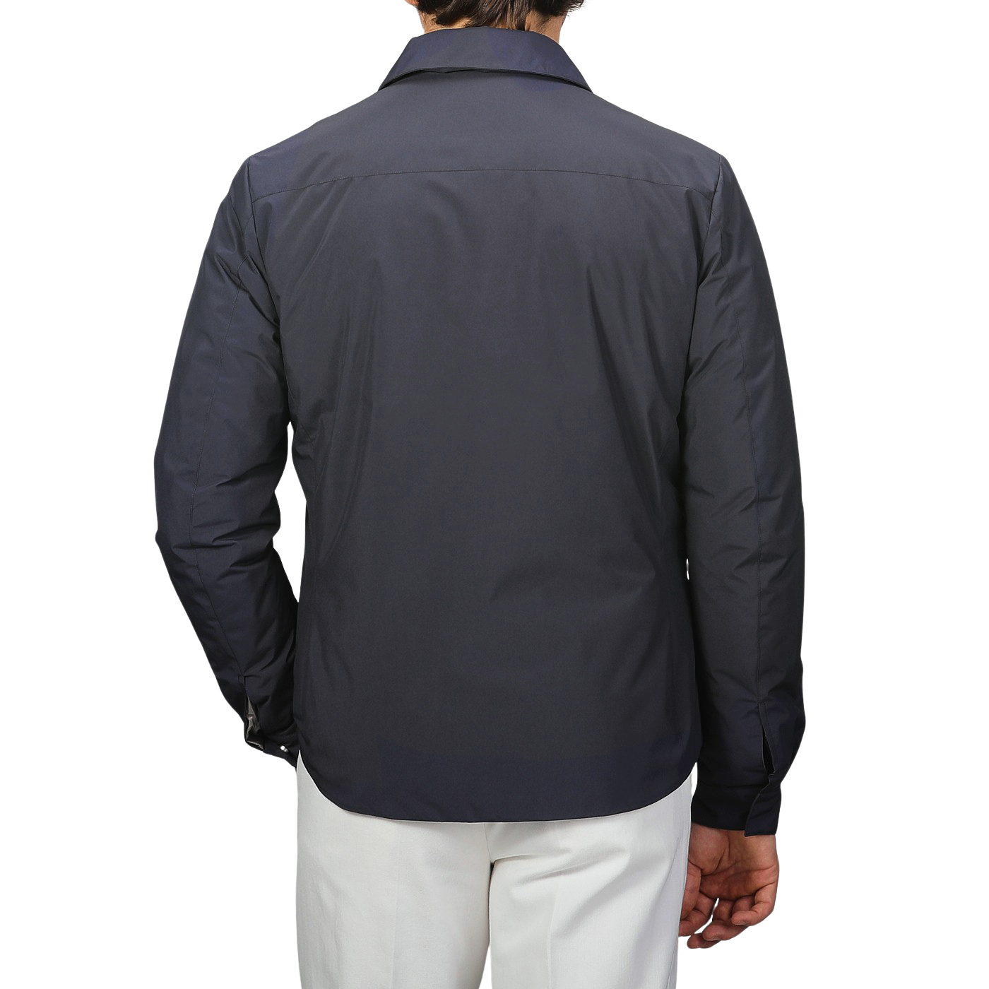 Against a plain backdrop, someone models Montecore's minimalist elegance by wearing the Dark Blue Light Down Waterproof Shirt Jacket with white pants, their back to the camera.