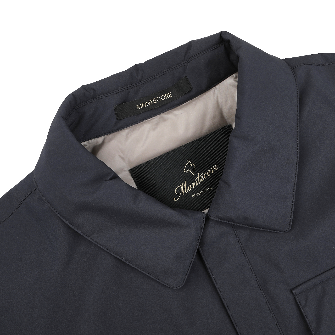 Close-up of a Montecore dark blue light down waterproof shirt jacket reveals visible "MONTECORE" outer label and inner label with logo and brand name. This contemporary piece features a folded collar and visible stitching.