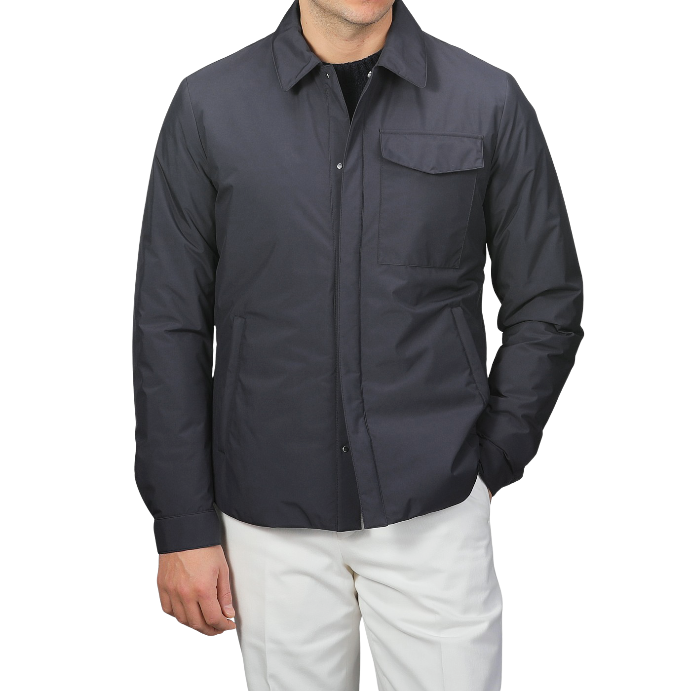 A man in a Montecore Dark Blue Light Down Waterproof Shirt Jacket and white pants stands against a plain background, showcasing contemporary outerwear at its finest.